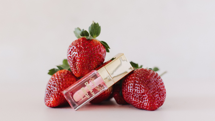 Lip balm with pink shade on strawberries against a white background