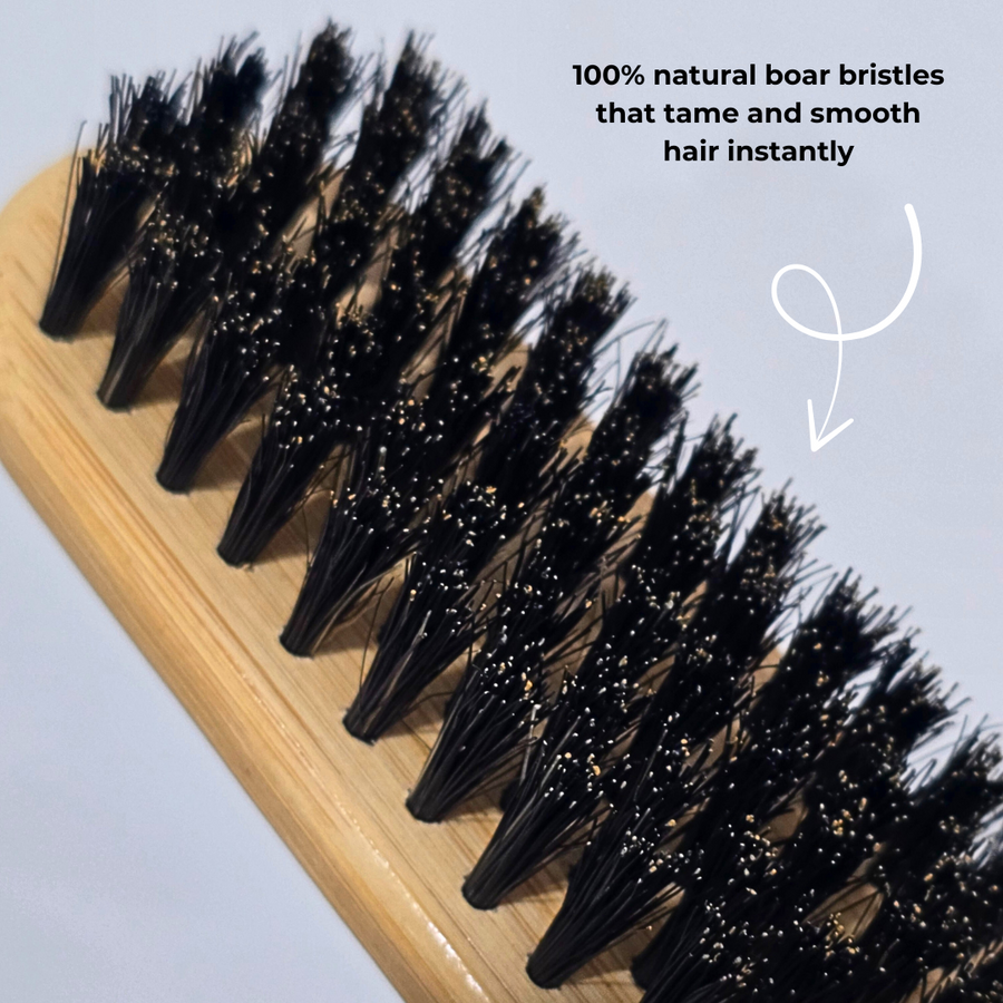 Hairbrush with black bristles on a wooden handle, labeled as having 100% natural boar bristles.